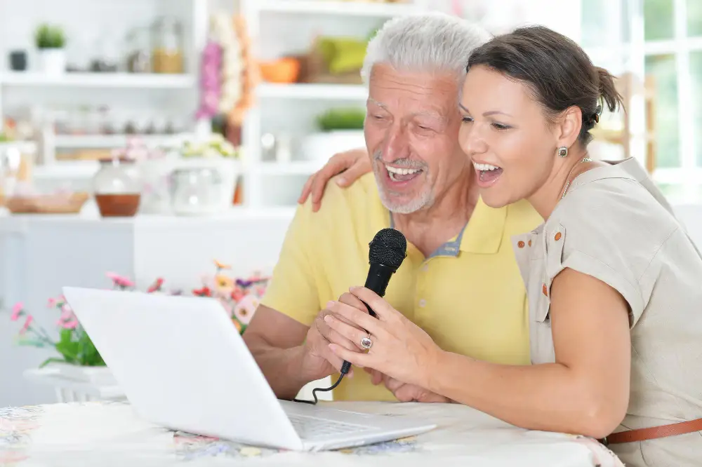 homme et femme chantant devant un ordinateur portable lors d'une activité virtuelle amusante pour renforcer l'esprit d'équipe