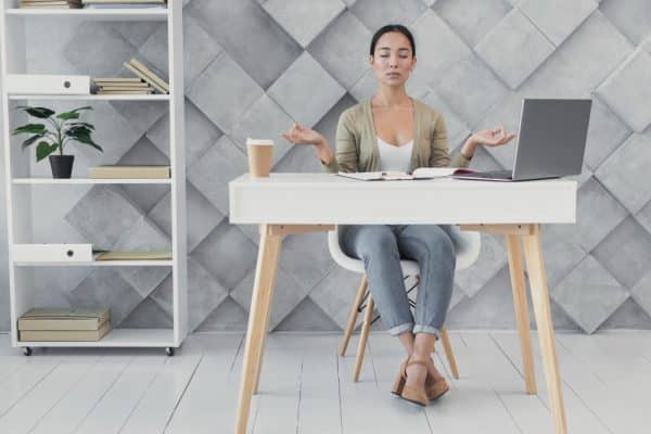 Frau, die in ihrem Home-Office an einem Online-Gruppenmeditationskurs teilnimmt