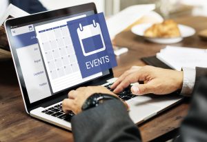 someone's hands working on a laptop, an event calendar is on the screen