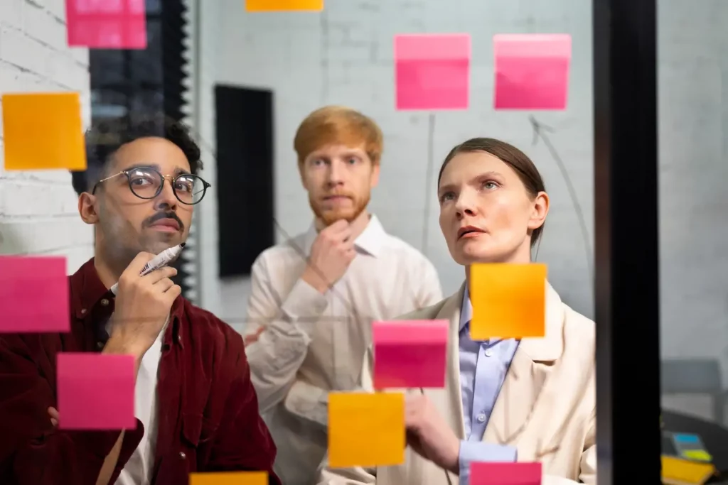 groupe d'organisateurs d'événements regardant un tableau avec des post-its résolution de problèmes