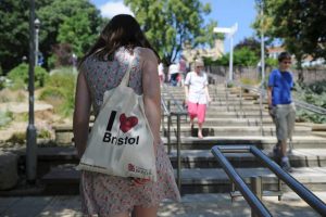estudiante caminando en el campus con una bolsa I love Bristol