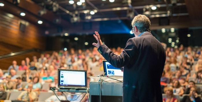 Spreker spreekt een auditorium toe en legt uit hoe je een succesvol evenement organiseert.