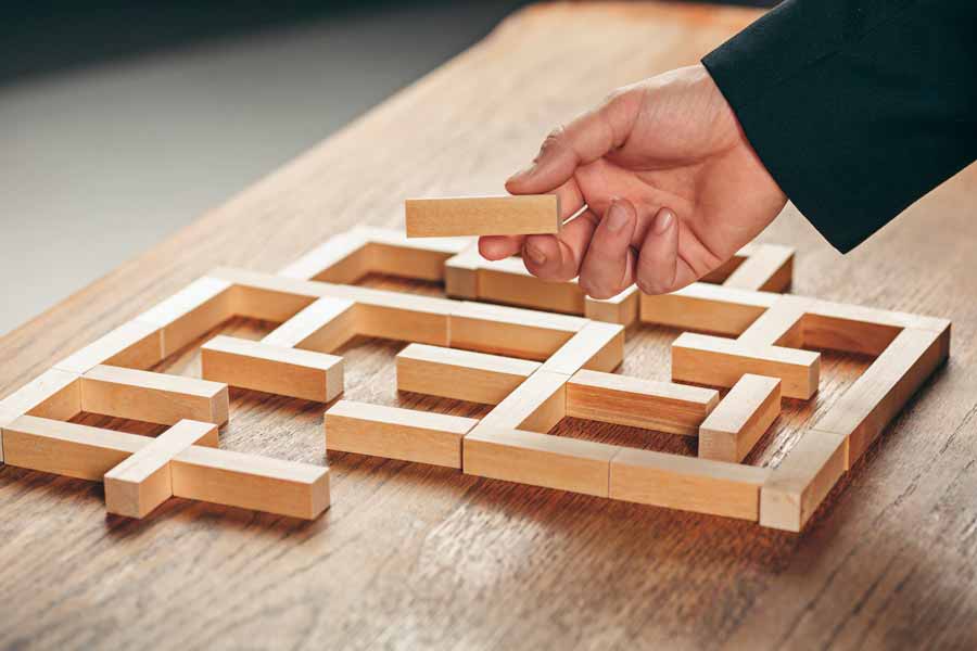 person's hand putting wooden pieces together as part of an employee training program