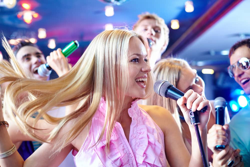 ryhmä ihmisiä laulamassa karaokea yritystapahtuman aikana