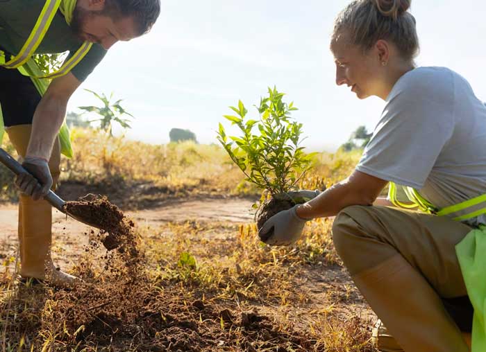 Two people outdoors planting trees to support an environmental cause