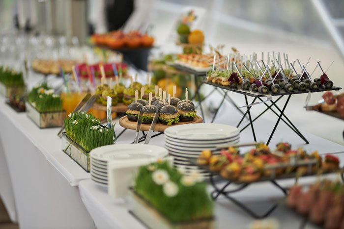 A catering table with a selection of bite-sized foods served on china and other reusable cutlery at a sustainable event