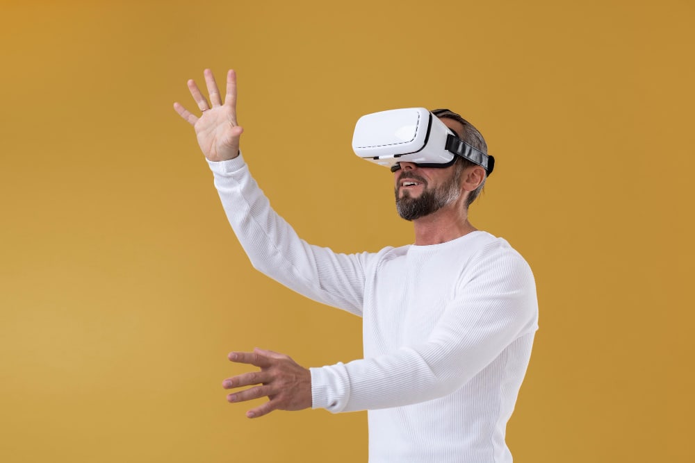 Older man wearing augmented reality glasses and reaching up and forward with both hands.