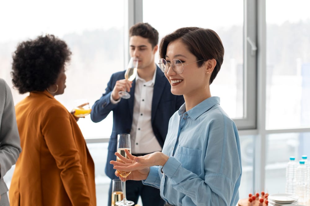A professional gathering in an office, where people are drinking champagne and celebrating their latest professional achievement.