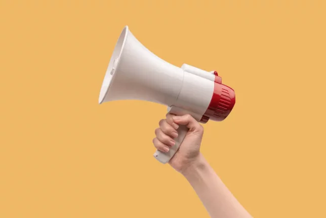 una mano caucásica femenina sosteniendo un megáfono