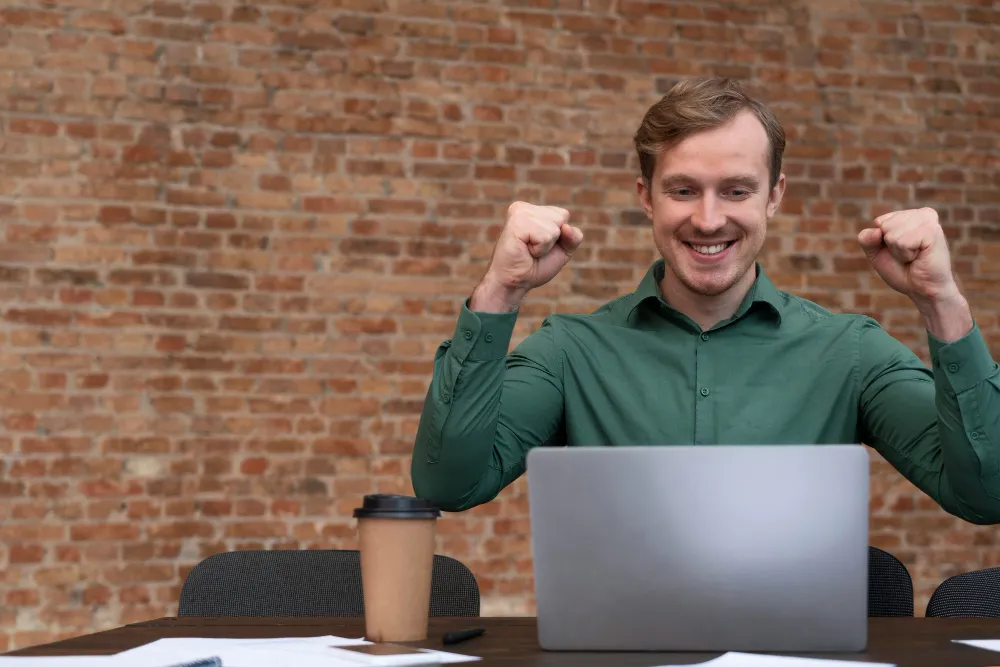a young professional man with his fists up celebrating that he is learning how to sell courses online successfully. 