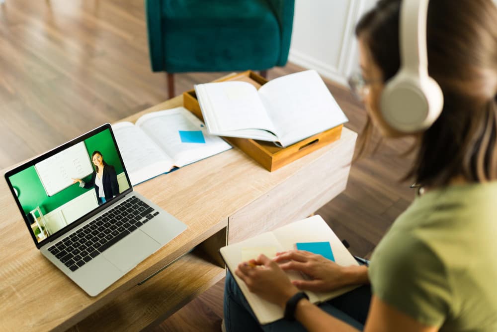 student som bär hörlurar och lyssnar på onlineföreläsning av en blandad lärandekurs.