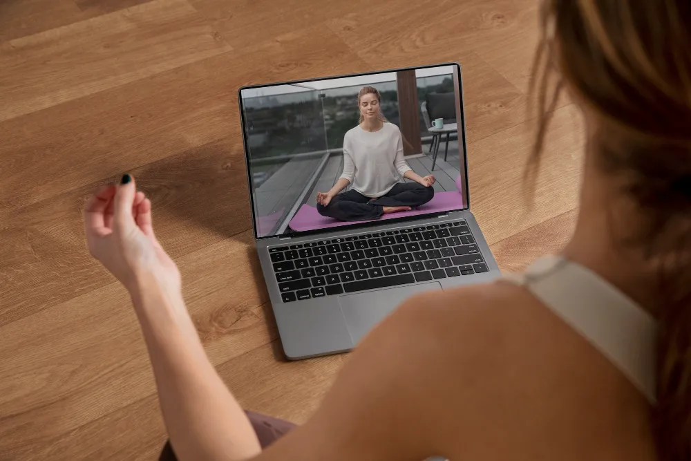 a woman taking yoga lessons virtually through her laptop.