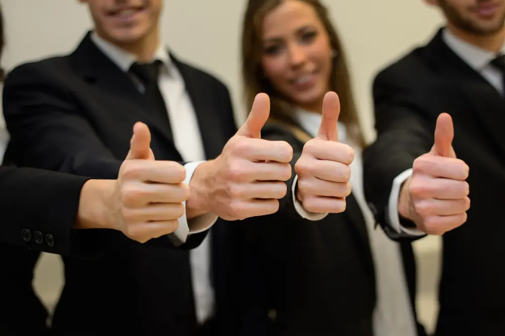 a group of professionals wearing black suits and showing their approval by sticking their thumbs up.