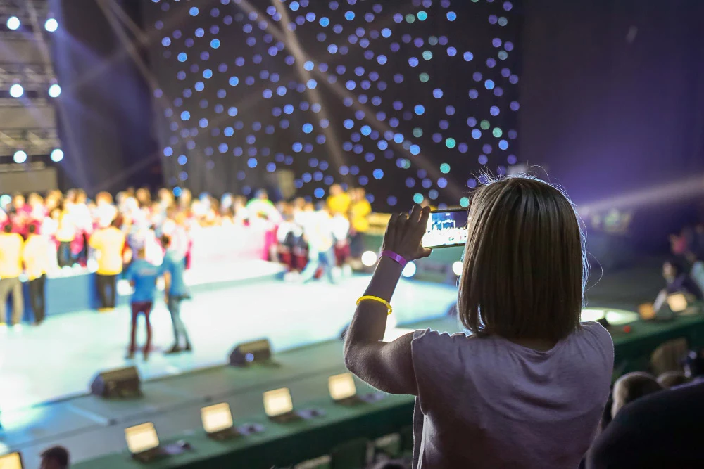 woman recording a live concert on her phone to post on an event listing website.