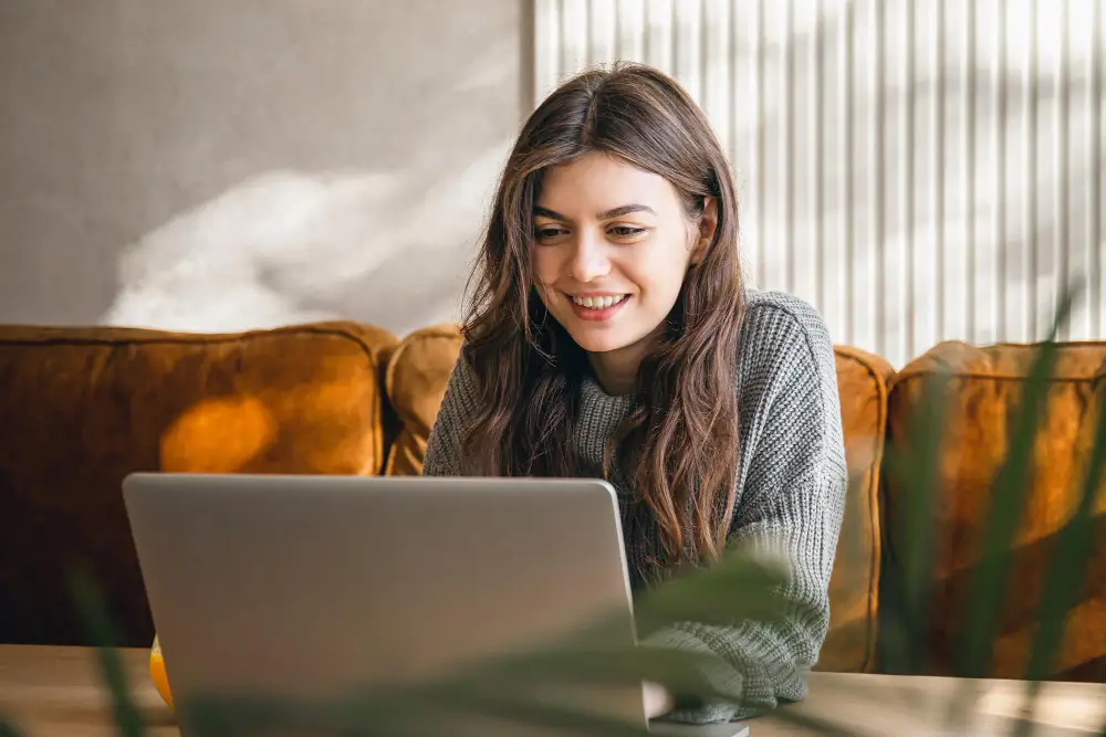 young woman smiling while using her laptop to research about the new trends in event technology.