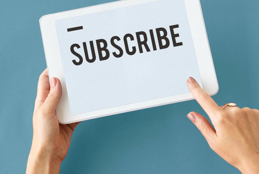 close-up of female hands hitting a subscribe button on a tablet with a blue background