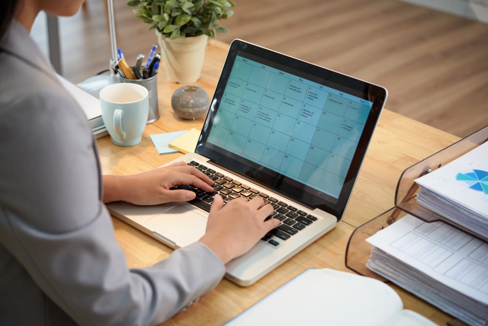 een vrouw die op haar laptop surft, zittend op een kantoor, op een lichte houten tafel