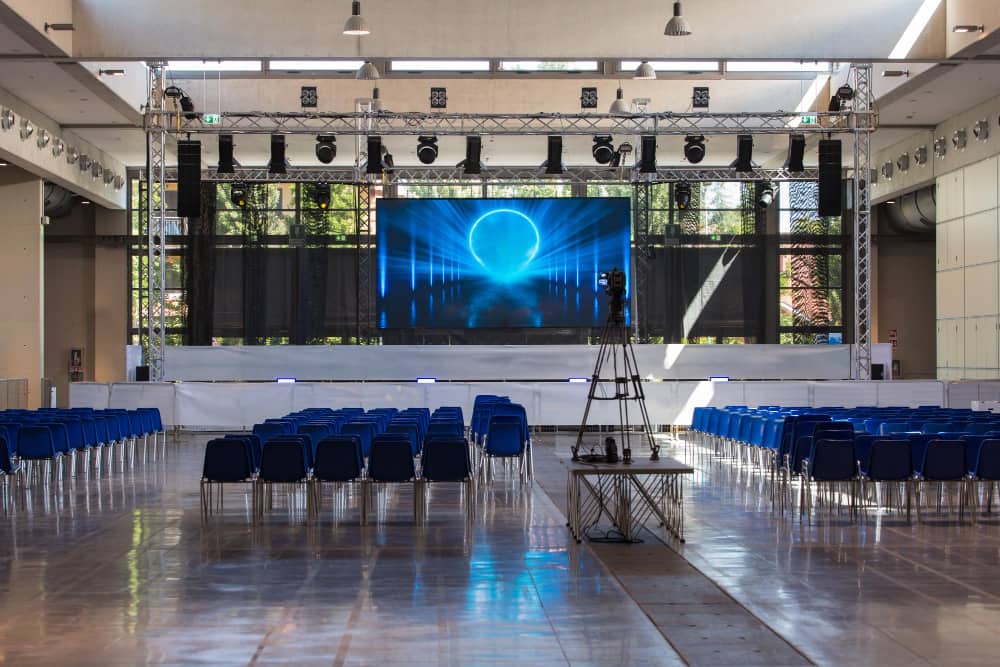 an empty venue with a stage and blue chairs.