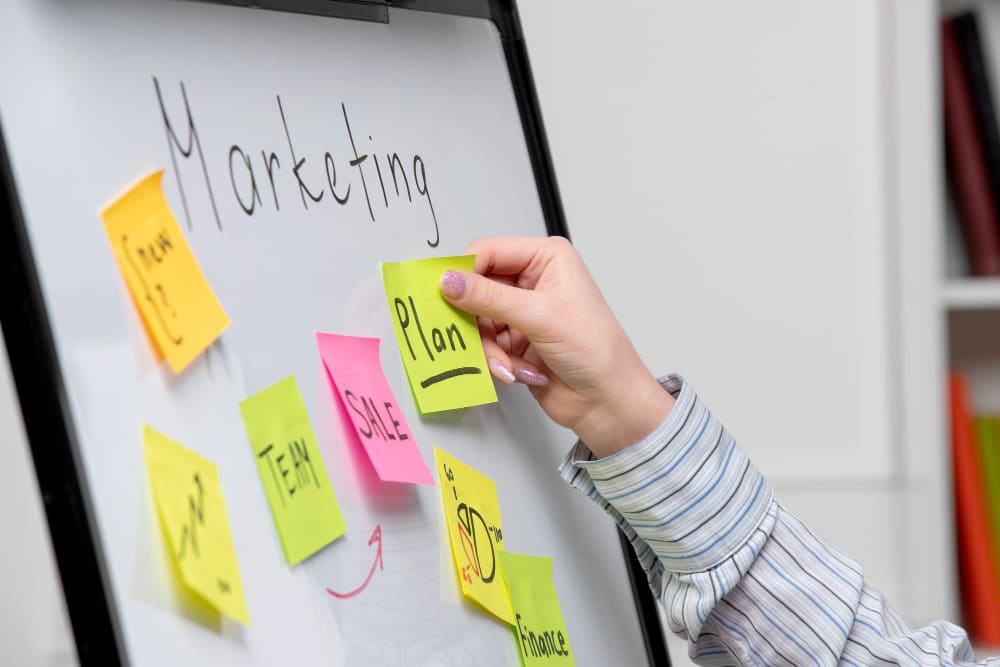 close up of white board with marketing plan and colorful sticky notes.