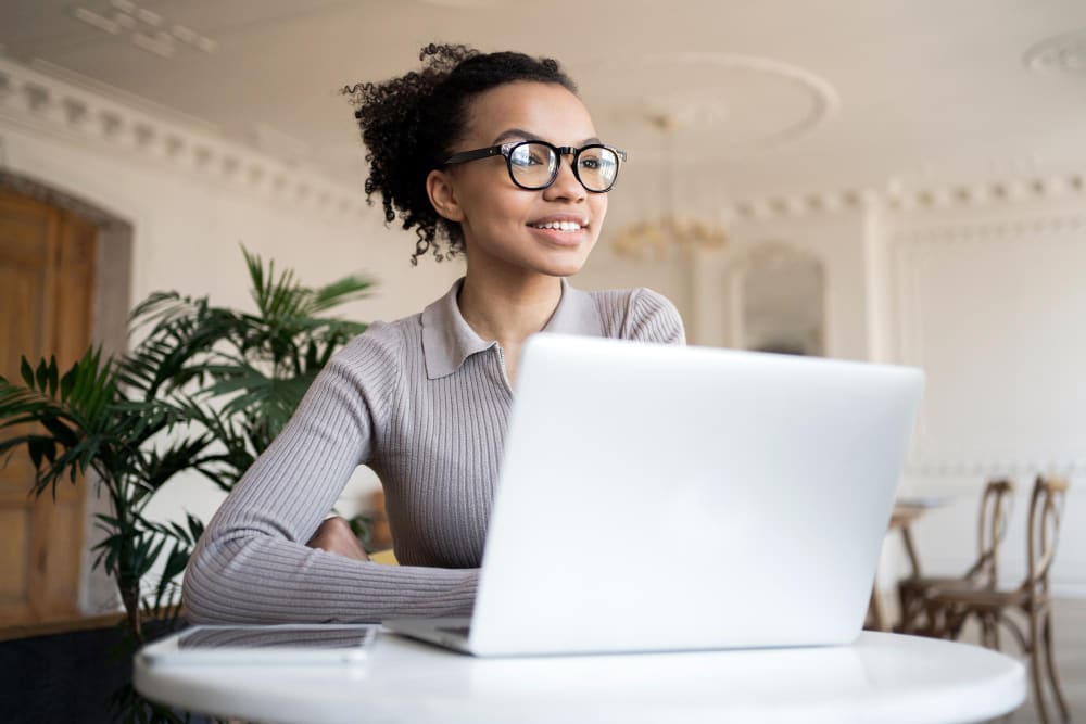 young female professional wearing glasses using her laptop to learn how start an event planning business