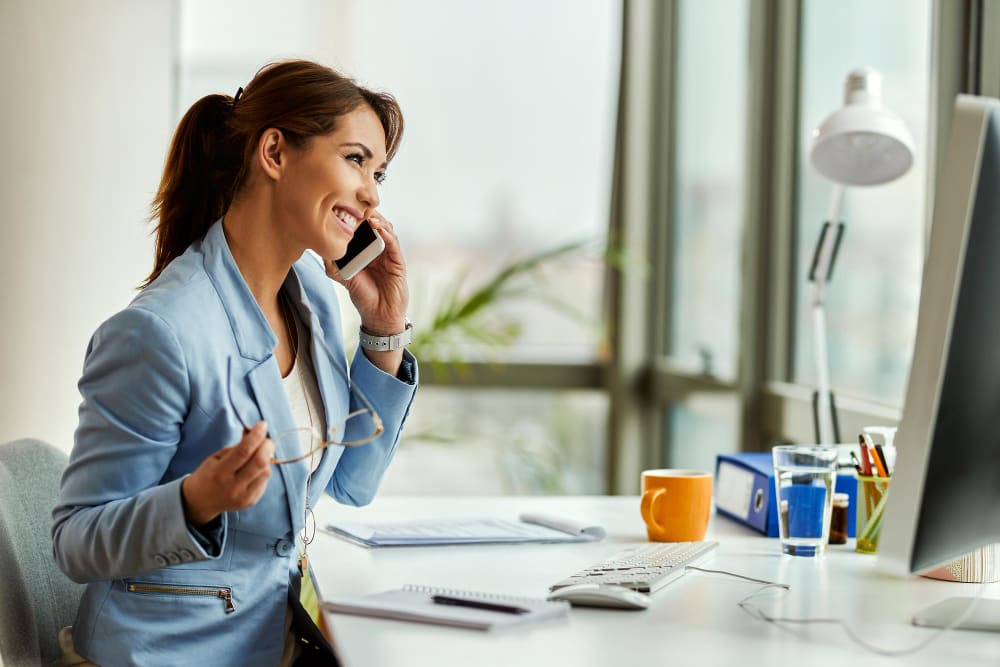 jeune femme portant un costume bleu souriant et parlant au téléphone.