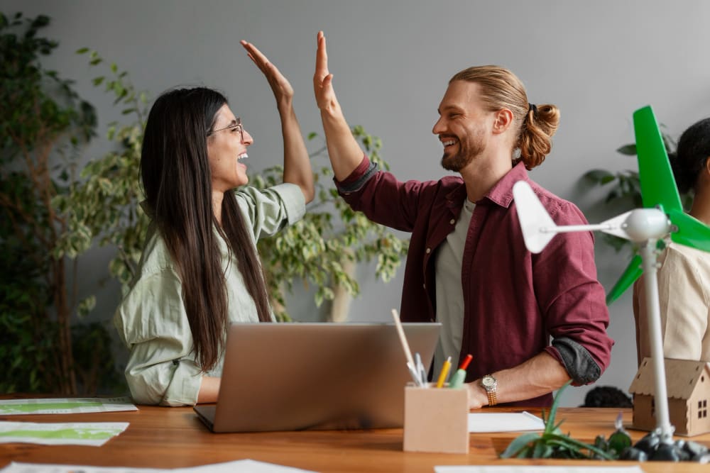 deux jeunes adultes souriant et faisant un high-five.