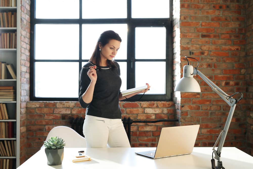 young professional woman at her home office standing in front of a laptop.