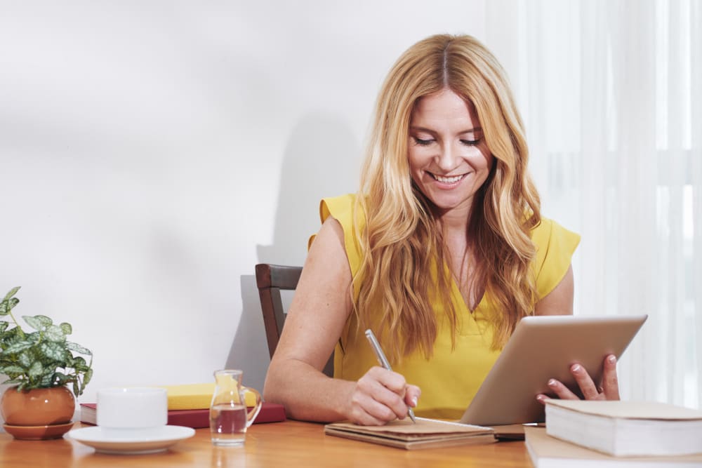 happy woman wearing a yellow blouse, taking notes.