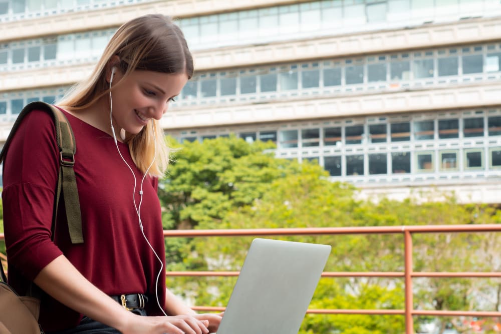 young female higher education student on her laptop with earphones in using artificial intelligence tools.