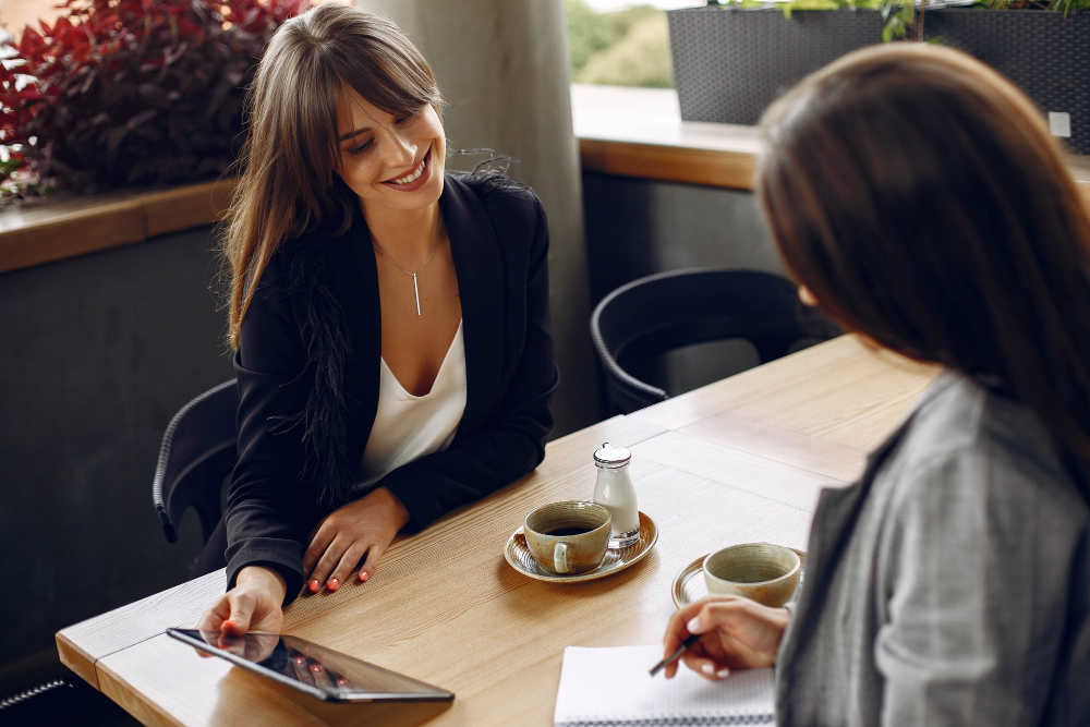 Two women at a coffee shop discussing how to customize an event planner contract template. 