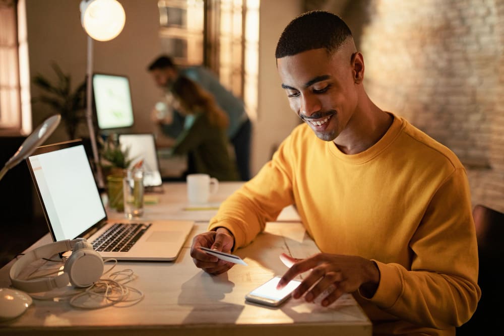 A young man entering his credit card information onto his cellphone.