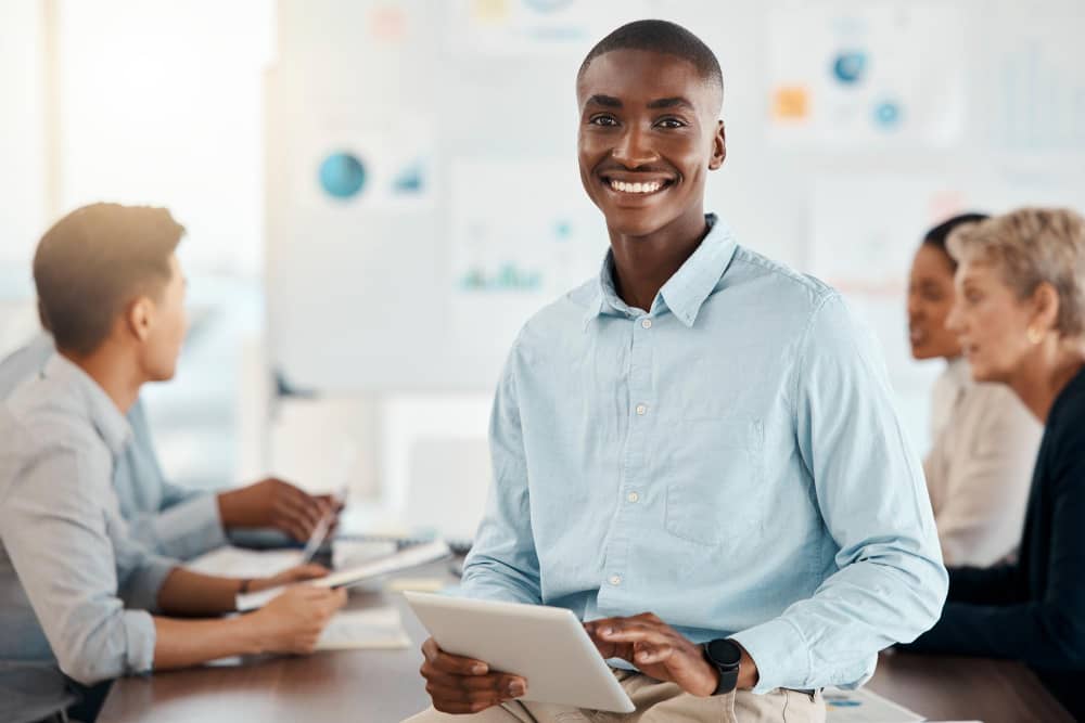 a young professional black male holding a tablet.