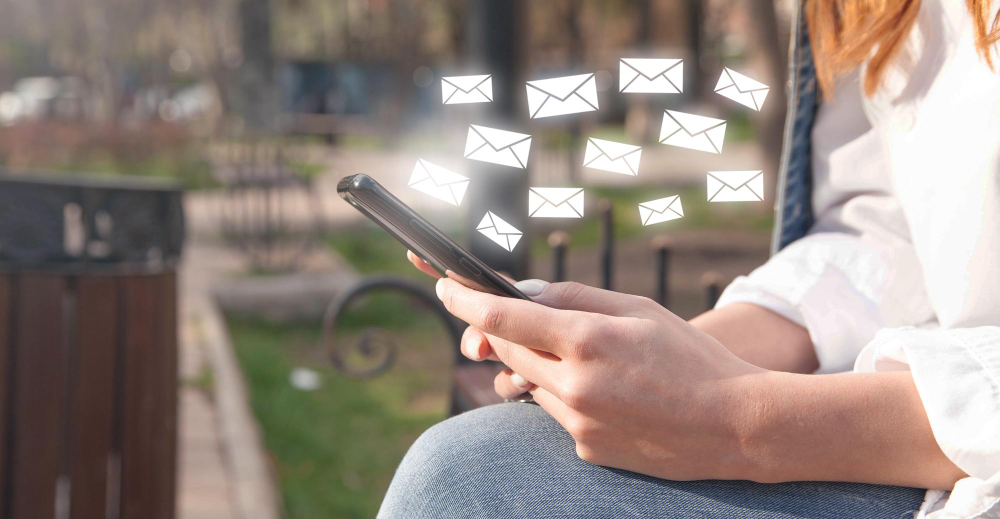Toma de primer plano de una mujer enviando correos electrónicos con su teléfono celular.