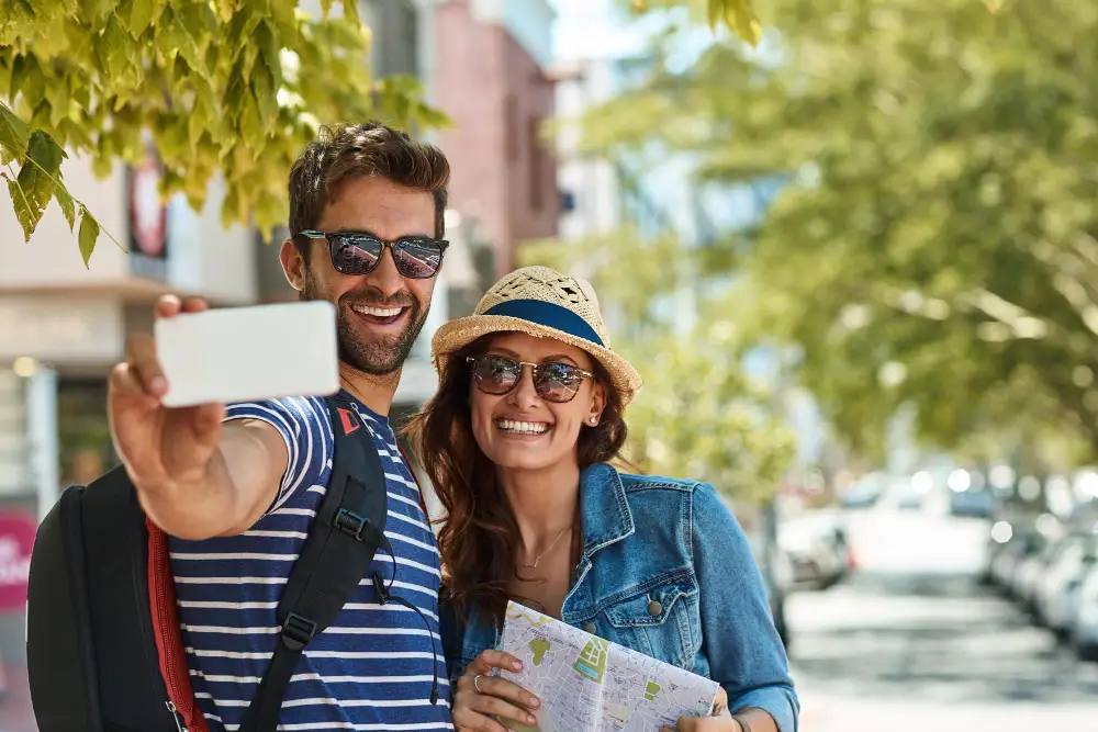 Two young travelers taking a selfie outdoors during a sunny day.