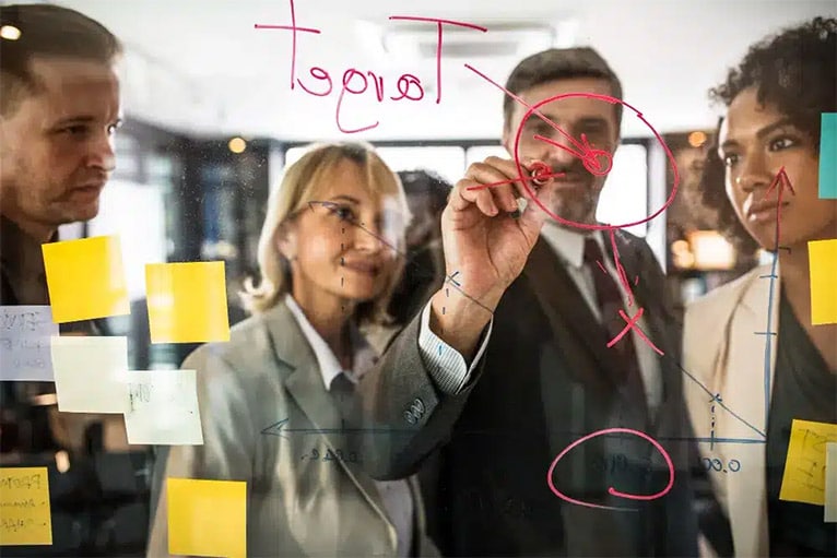 un team di professionisti che scrive su lavagne di vetro, pianificando insieme strategie.