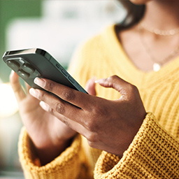 Kvinde bruger sin mobiltelefon til at finde og tilmelde sig programmer, aktiviteter og medlemskabsmuligheder